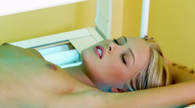Blondine oben ohne im Solarium